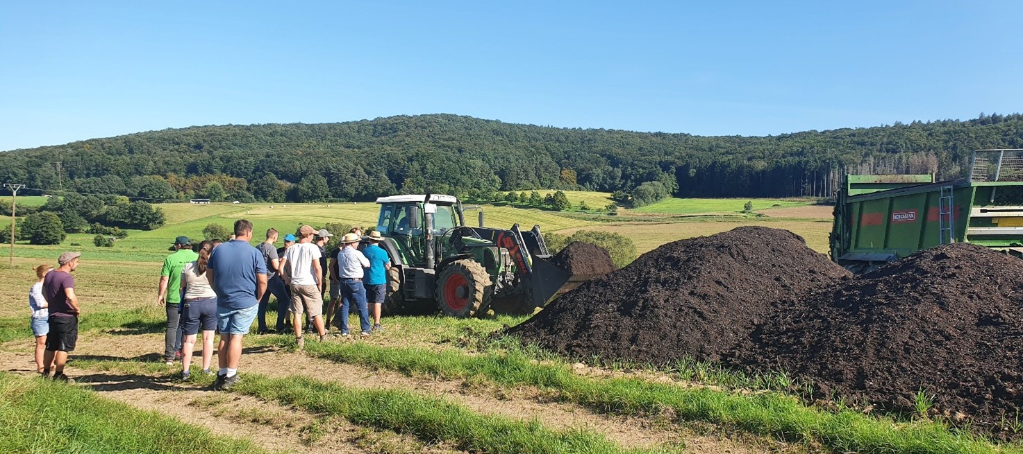 Kompost-Traktor auf Feld grüner Traktor mit Kompost-Anhänger auf gelbem Feld